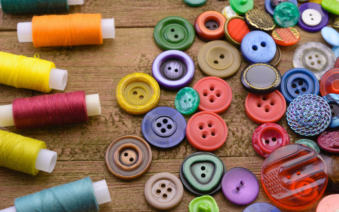 Image of brightly colored buttons and spools of thread spread out, to illustrate a story about how a tiny button led a product to fail, and why smart product design matters.