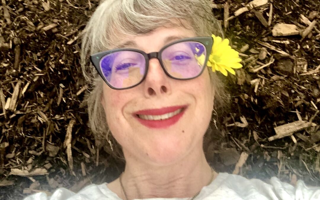 Author smiling and resting on a pile of mulch.